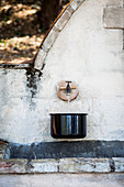 Kochtopf mit Wasser am Steinbrunnen