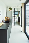 Black kitchen counter with sink and open doorway leading into open-plan living area