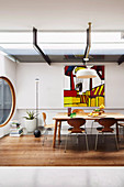 Dining area in designer apartment with dining table, round window and abstract wall painting