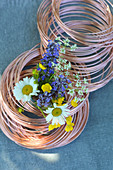 Posy of wild summer flowers in roll of copper wire