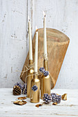 Bottles sprayed gold and used as candlesticks arranged with pine cones and leaves