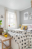 Cross-patterned throw on double bed in light-flooded bedroom