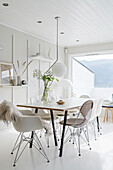 Dining table and various Eames chairs in white interior