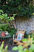 Rattansessel an der Natursteinmauer im mediterranen Garten