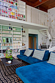 Blue velvet modular sofa in maisonette apartment with white winding staircase and gallery