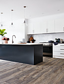 Modern, open-plan kitchen with black island counter and white cupboards