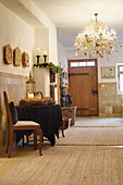 Brown tablecloth and Advent wreath on round table and chandelier with opulent Christmas decorations in rustic hallway