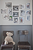 Family photos in silver frames on wall above two chairs