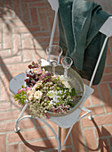 Tablett mit frischen Blumen und Gläsern auf einem Stuhl