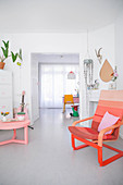 Coffee table and armchair in shades of red and pink in white, light-flooded interior