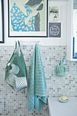 Netzbeutel mit Toilettenpapier und Handtuch im Badezimmer mit Mosaikfliesen