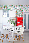 Dining area, red fridge and white kitchen cabinets against floral wallpaper