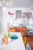 View past spring flowers on dining table to retro sideboard and glass-brick interior wall