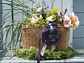 Summer bouquet of roses, grasses and lavender in basket in wreath of lavender