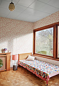 Patchwork blanket on bed in vintage-style room with retro wallpaper