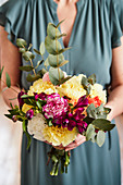 A woman holding a birthday bouquet with carnations and eucalyptus