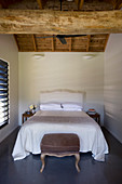 Doppelbett in schlichtem Schlafzimmer mit Holzbalken