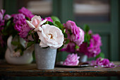 Pink and white roses in metal vase on wooden table