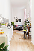 Schmaler Wohnraum mit Küchenzeile, Arbeitstisch und Sitzbereich