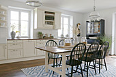 Dining table and dark chairs on rug in country-house kitchen