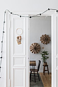 DIY-Adventskalender und Lichterkette an weißer Tür, Blick ins weihnachtlich dekorierte Esszimmer