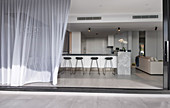 Blick durch offene Terrassentür ins luxuriöse Wohnzimmer mit Küche