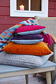 Cushions with covers in autumnal colours and knitted blanket