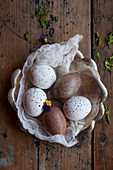 Speckled eggs on piece of muslin in rustic bowl