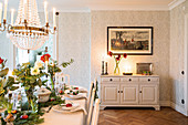 Hunting scene above sideboard and long, festively set dining table in dining room
