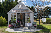 Idyllic summerhouse made from old windows in summery garden