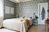 Doppelbett mit Tagesdecke in Beige und Tapete in Grautönen im Schlafzimmer