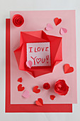 Love note in origami envelope on pink and red paper