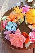 Wreath of colourful paper flowers on plate in sunshine