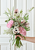 Hand holding early summer bouquet in pastel shades