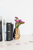 Books and flowers in gold vase