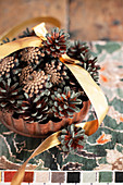 Christmas arrangement of pine cones and gold ribbon in rusty cake tin