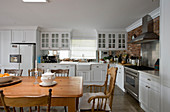 Kitchen with white cabinets and solid wooden dining table and chairs