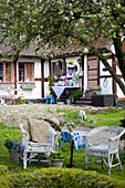 Wicker chairs in seating area in garden outside old half-timbered house