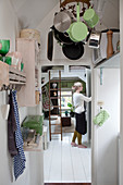 Pans hung from rack suspended from ceiling and woman opening cupboard
