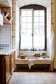 Tall lattice window in rustic country-house kitchen with old stone sink