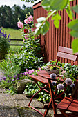 Wind-protected seating area and hollyhocks on wooden wall