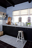 Counter with dark doors and granite worksurface in kitchen with grey-blue walls