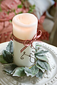 White pillar candle with decorative ribbon, 'Jul' wire words and leaf wreath