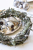 Christmas wreath made of branches with moss and lichen and silver plate with Christmas decorations