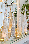 DIY paper cone shaped Christmas trees, tea lights, animal figures, and fairy lights in front of the mirror