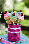 Mini cupcakes with raspberries in glass with crochet cover for garden party