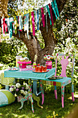 Girlande überm bunt gedeckten Tisch zur sommerlichen Party im Garten