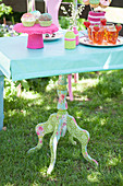 Old table with colourful fabric decoupage anc crocheted accessories in garden