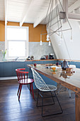 Langer Esstisch mit verschiedenen Stühlen in Wohnküche mit blau-grauen Unterschränken
