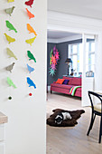 Garlands of colourful paper birds on wall next to open doorway leading into open-plan living room